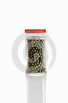Green peppercorn in glass jar on white background