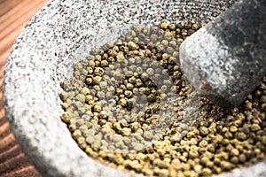 Green peppercorn seed in granite mortar or pestle