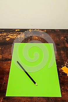 A green piece of paper with a pencil on it