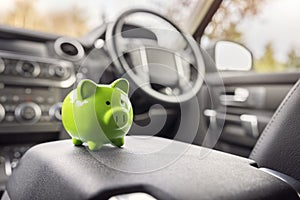 Green piggy bank money box inside car, vehicle purchase, insurance or driving and motoring cost