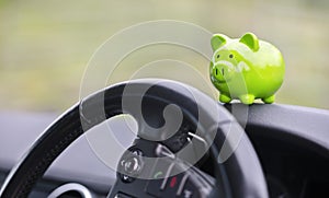 Green piggy bank money box inside car, vehicle purchase, insurance or driving and motoring cost