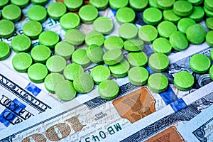 Green pills on the background of one hundred dollar bills