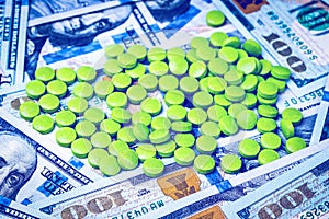 Green pills on the background of one hundred dollar bills. The concept of the expensive cost of healthcare