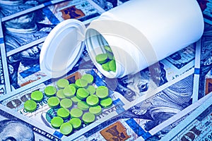 Green pills on the background of one hundred dollar bills. The concept of the expensive cost of healthcare or financing medicine.