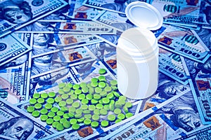 Green pills on the background of one hundred dollar bills. The concept of the expensive cost of healthcare or financing medicine.