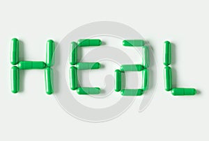 Green Pills capsules in shape of word Heal. Life concept isolated.