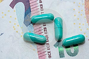 Green pills lie on pile of euro bills background
