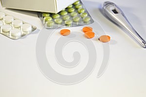Green pills in a package, colorful pills and a thermometer