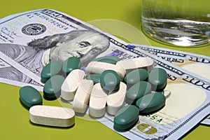 Green pills scattered on one hundred dollar bills. Cost of the healthy life concept