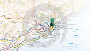 A green pin stuck in Barcelona on a map of Spain