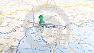 A green pin stuck in Thessaloniki on a map of Greece