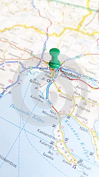 A green pin stuck in Thessaloniki on a map of Greece portrait