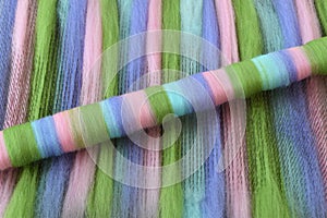 Green, pink, blue, and purple wool rolag on a blending board