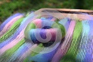 Green, pink, blue, and purple wool rolag coil on a blending board