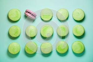 Green and pink macaroons on blue background. Pink is single