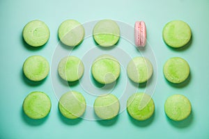 Green and pink macaroons on blue background. Pink is single