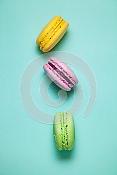 Green, pink and yellow macaroons on blue background