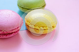 Green, pink and yellow macaroons french biscuits with fillings on blue and pink backgrounds