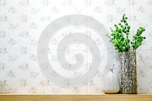 Green plant in different vases put on wooden shelf front of flowers pattern tile in the toilet