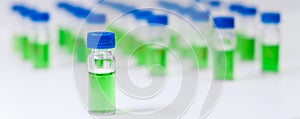 Green plant extract in HPLC vial with blue cap on white background. Developing of pharmaceuticals or vaccine concept