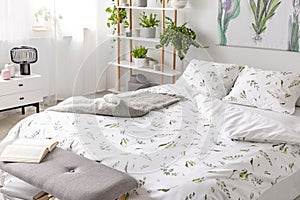 Green plant pattern on white bedding and pillows on a bed in a nature loving bedroom interior