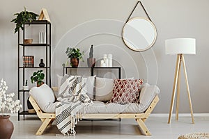 Green plants in pots, candles and books on metal shelves in beige scandinavian living room