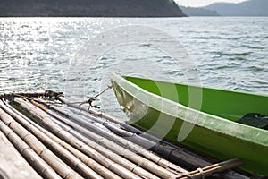 Green plastic boat parked at bamboo raft on water surface. this
