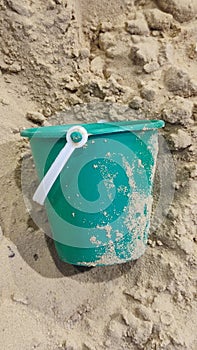 green plastic bucket lies in the sand, children& x27;s toy, object, beach