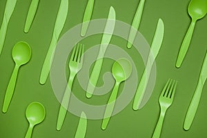 Green plastic forks, spoons, knifes on green paper. Set of plastic cutlery in different spoons forks knives and eco