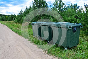 Green plastic garbage containers installed along the road in a modern European village. The concept of separate garbage collection