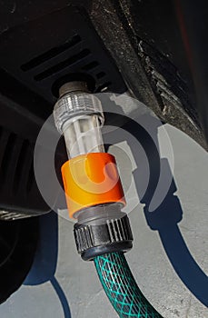green plastic garden hose pipe with orange plastic snap connectors connected to a high pressure washer for cars