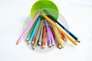 A green plastic glass with colored pencils