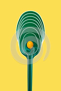 Green plastic picnic spoon on a yellow background