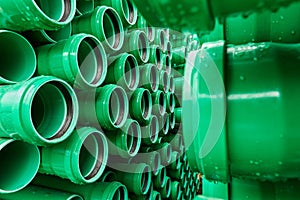 Green plastic pipes lie in rows