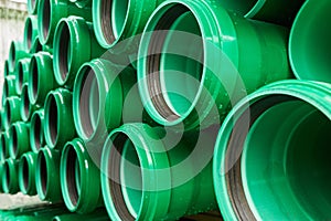 Green plastic pipes lie in rows
