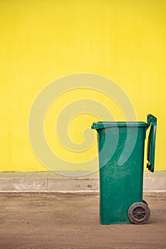 Green plastic trash container on wheels on the background of a y