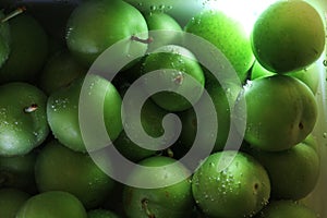 Green plums in the water with defocused shot can be used as a background