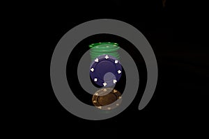 Green pocker chips stack with a blue chip in front isolated on black with reflection