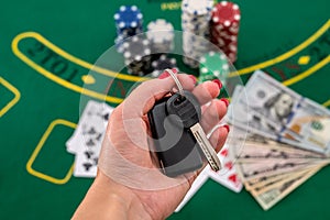 on a green poker table are cards, dollars, chips and a woman& x27;s hand holds the cliffs of the car