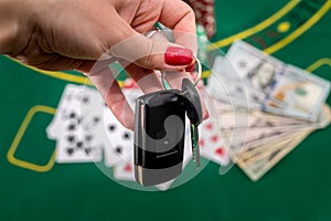 on a green poker table are cards, dollars, chips and a woman& x27;s hand holds the cliffs of the car