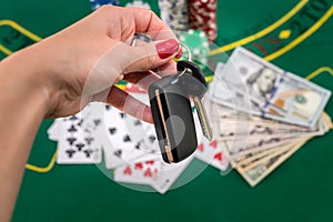 on a green poker table are cards, dollars, chips and a woman& x27;s hand holds the cliffs of the car
