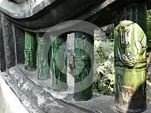 Green Pottery Bamboo columns in a stone wall. Shanghai, China, 2018.