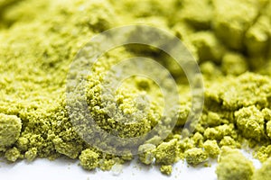 Green powder Japanese matcha tea close-up. The powder contains an admixture of white granules of coconut milk. Matcha latte in dry