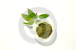 Green powder of Japanese matcha tea on a platter, isolated on a white background.