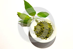 Green powder of Japanese matcha tea on a platter, isolated on a white background.