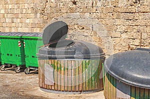 Green public garbage trash container at street with open coverlid