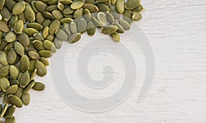 Green pumpkin seeds on wooden white background. Copy space