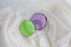 Green and purple macarons on white mesh.
