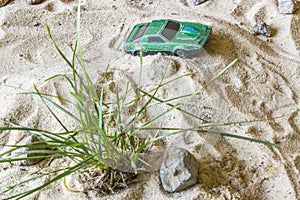 A green race car on the track rides over the hill.