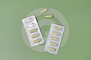 Green rectal pills or suppositories for anal or vaginal use with blister on green  background. Medicines for alternative
